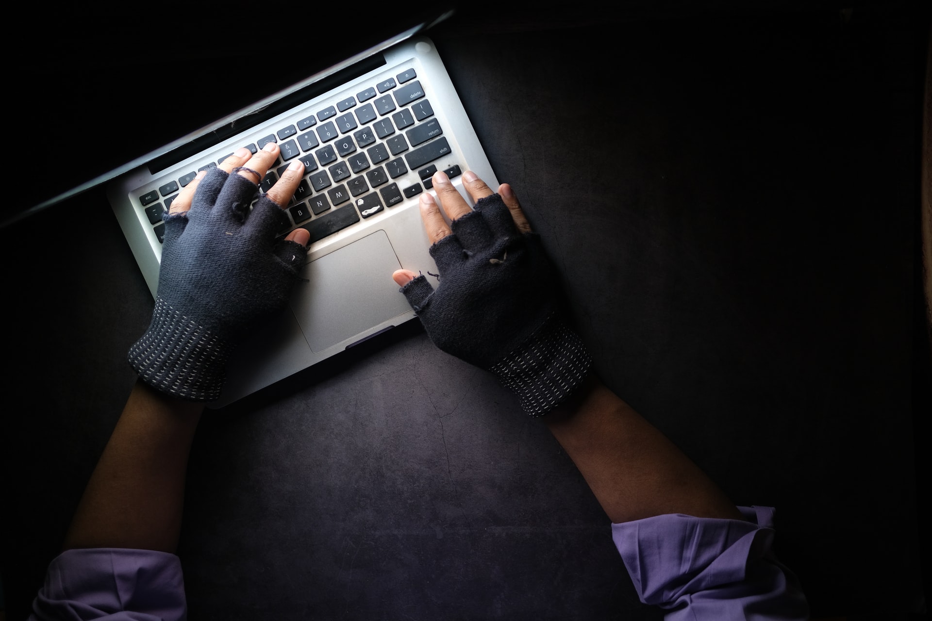A pair of hands typing on a laptop in a dark room